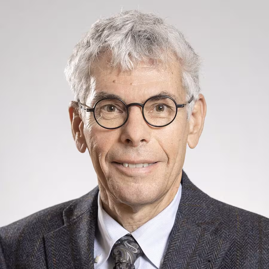 A chest-length portrait of Stefan Maul. He is wearing round glasses, has short gray hair, and is smiling at the viewer. He is wearing a shirt, a tie, and a suit jacket.