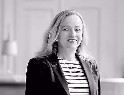 Portrait of a woman in black and white. An older woman smiles at the viewer. She has shoulder-length hair.