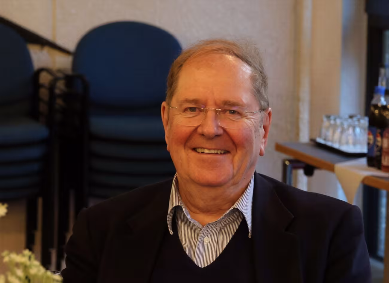 Michael Welker smiles at the camera. He is in his late 70s, wears glasses, and has a high forehead.